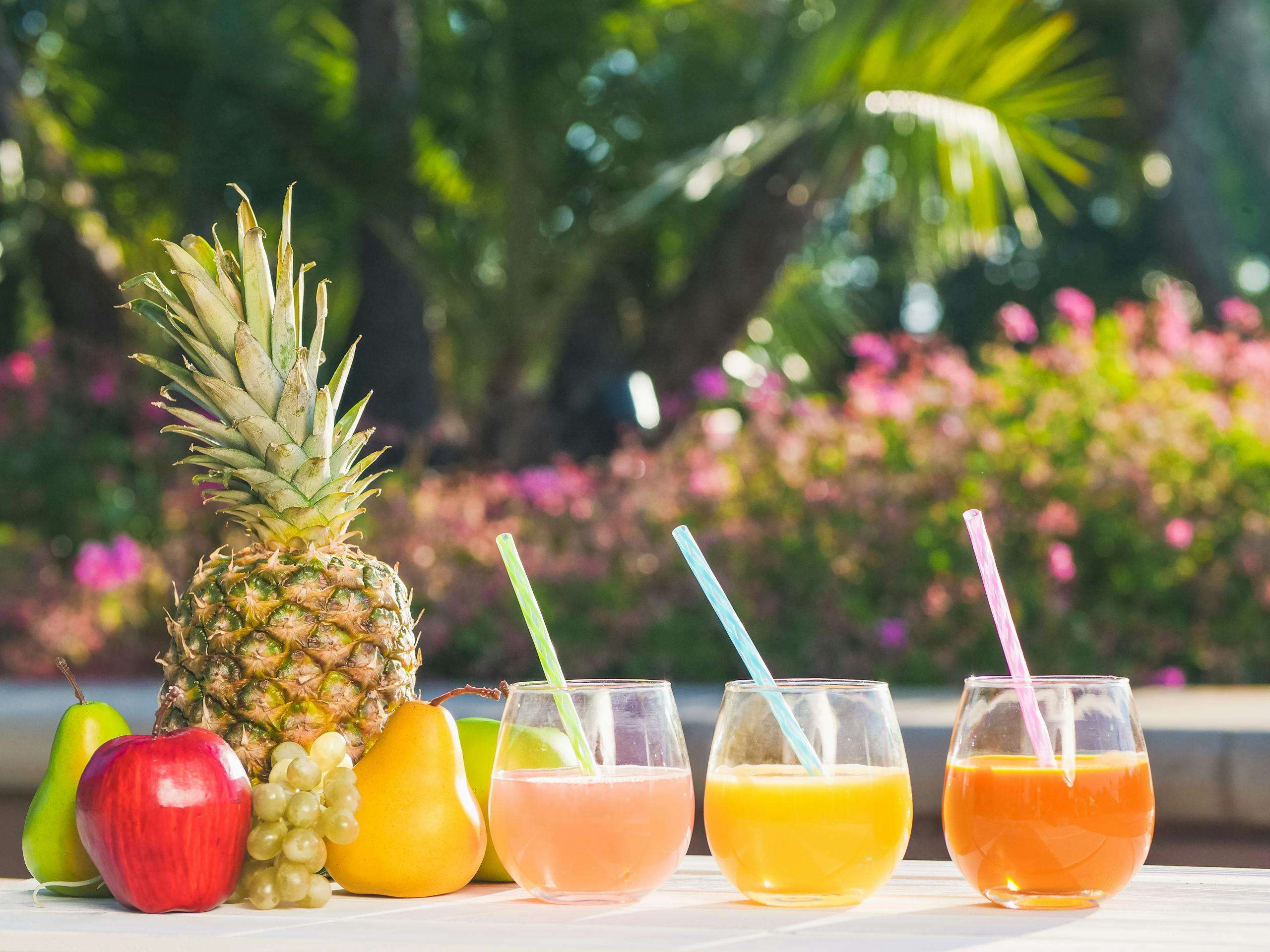 A colorful trio of drinks: a tropical smoothie, a citrus-infused cocktail with ice, and a berry refresher in elegant glassware.
