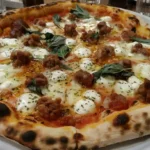 Freshly baked pizza with melted cheese, golden crust, and classic toppings on a wooden board in a cozy kitchen setting.