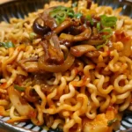 A bowl of saucy ramen noodles topped with mushrooms, chopped scallions, and vegetables.